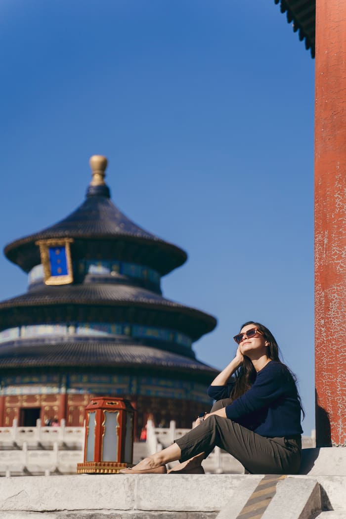 una mujer tomandose un foto con el templo del cielo de fondo en beijing