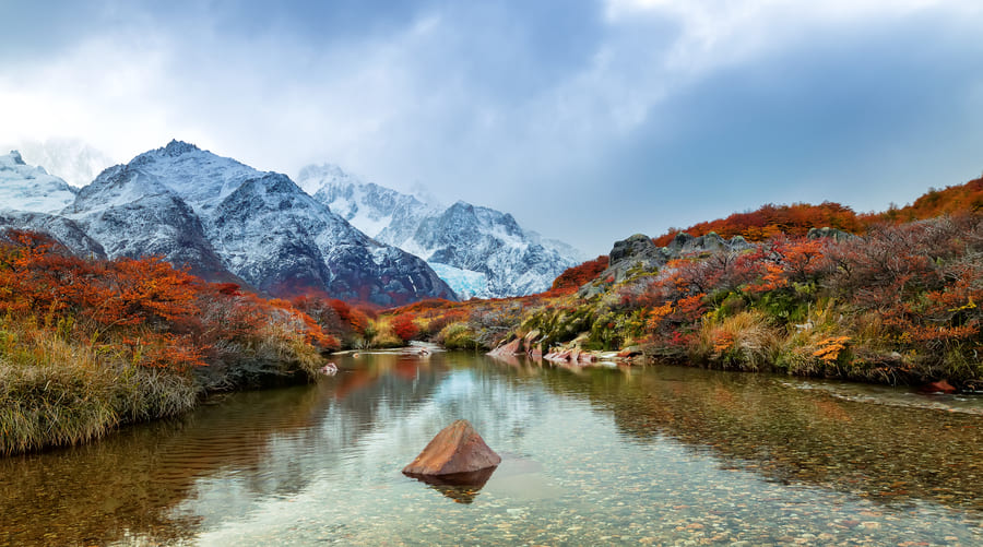 Un lago en Yunnnacon montañas y al fondo montañas nevadas